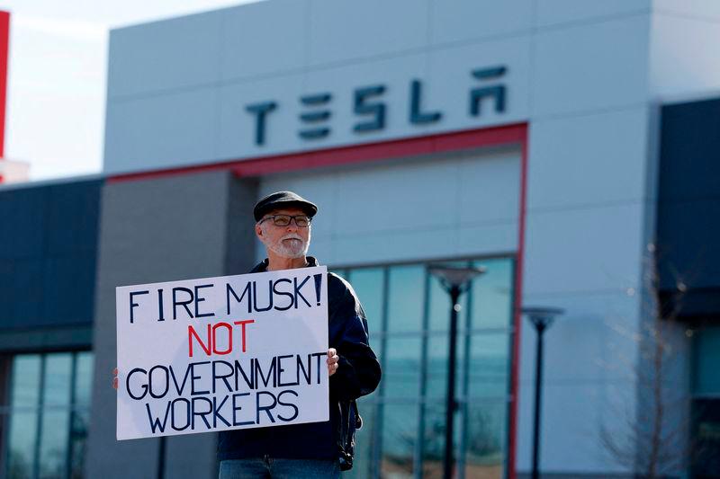 People participate in a protest against Elon Musk outside of a Tesla dealership in West Bloomfield, Michigan on March 13, 2025