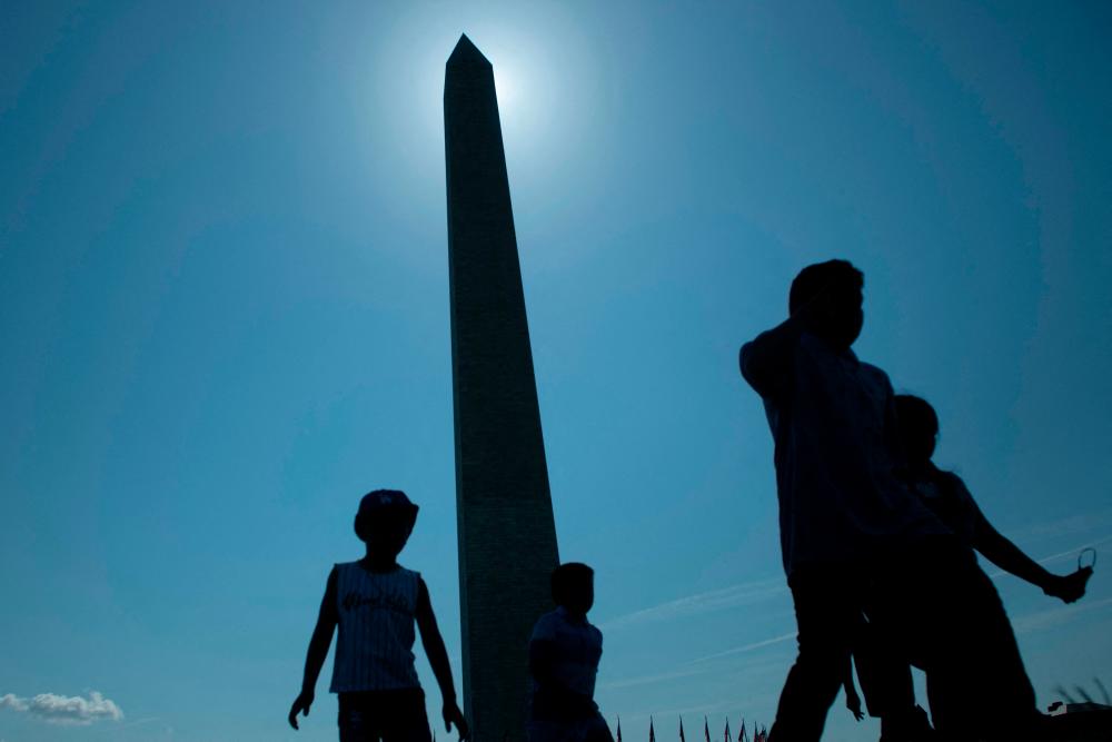 People walk near the Washington Monument as it opens for interior tours after being closed during the Covid-19 pandemic on July 14, 2021, in Washington, DC. – AFP