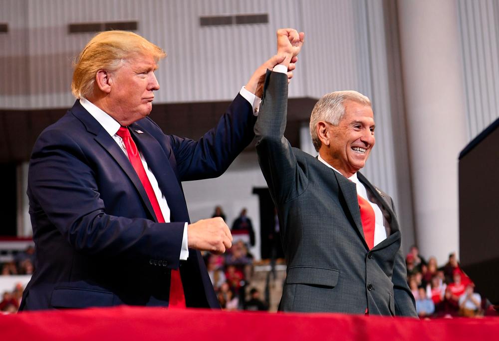 US President Donald Trump (L) cheers for Louisisna Republican Gubernatorial candidate Eddie Rispone during a Keep America Great rally in Bossier City, Louisiana on Nov 14. — AFP