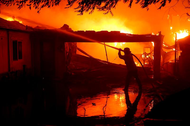 A firefighter sprays water on a burning home while battling the Eaton Fire on January 08, 2025 in Altadena, California. Fueled by intense Santa Ana Winds, the Palisades Fire has grown to over 2,900 acres and 30,000 people have been ordered to evacuate while a second fire has emerged near Eaton Canyon in Altadena. - Justin Sullivan/Getty Images/AFP