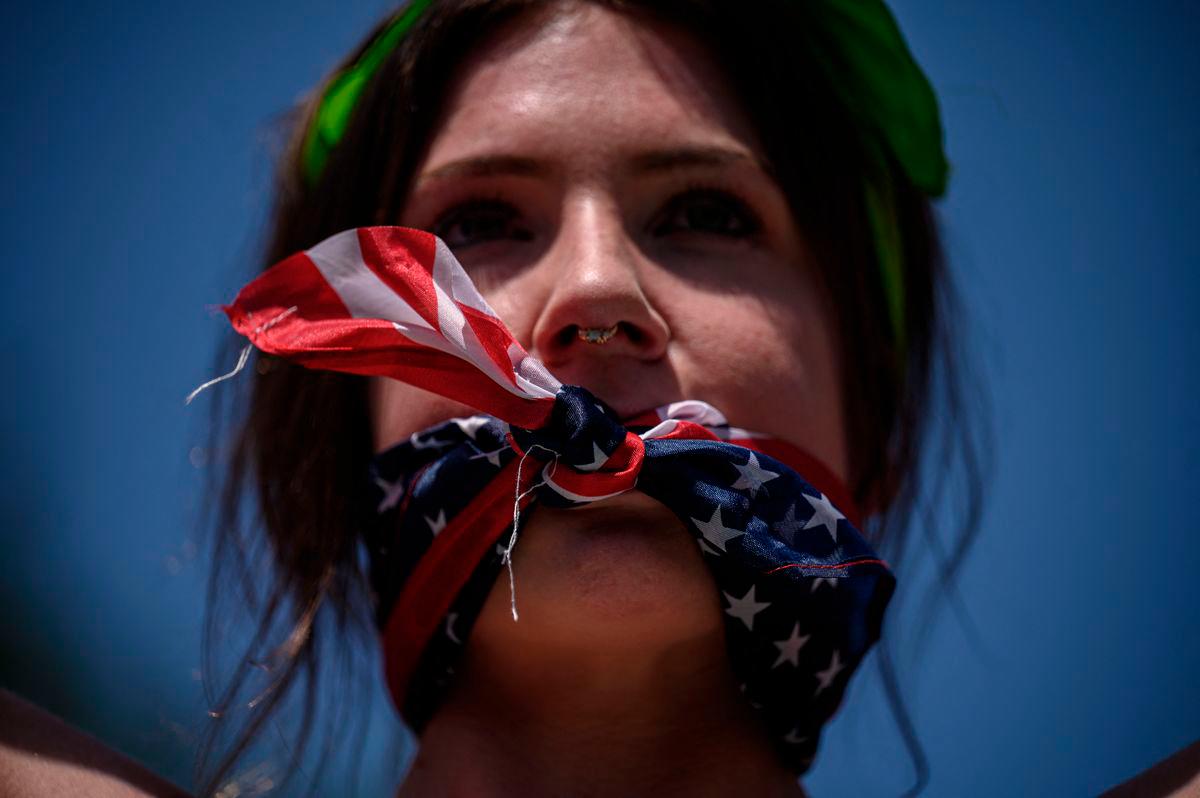 A reproductive rights activist, gagged by a scarf in the colors of the US flag, marches during a protest against a recent Supreme Court ruling on abortion rights, in New York, July 4, 2022. (Photo by Ed JONES / AFP)