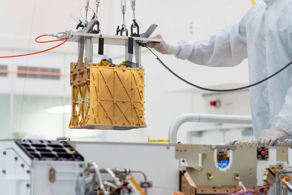 This handout photo obtained April 21, 2021 and released by NASA/JPL shows technicians in the clean room carefully lowering the Mars Oxygen In-Situ Resource Utilization Experiment (MOXIE) instrument into the belly of the Perseverance rover in the cleanroom at NASA's Jet Propulsion Laboratory, in Pasadena, California in March 2019. –AFP