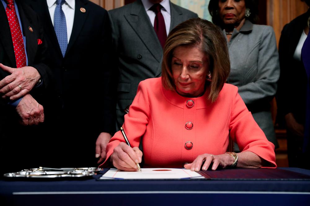 US Speaker of the House Nancy Pelosi (D-CA) signs the articles of impeachment against President Donald Trump during an engrossment ceremony in the Rayburn Room at the US Capitol on Jan 15, in Washington, DC. — AFP