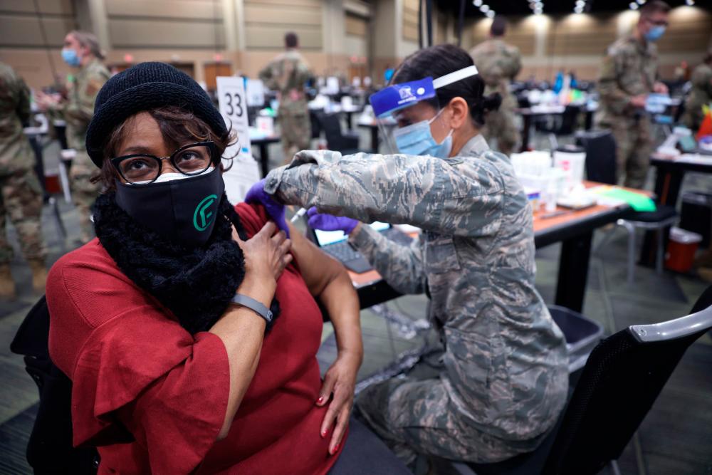 SrA Serena Nicholas of the Illinois Air National Guard administers a COVID-19 vaccine to Larcetta Linear at a mass vaccination center established at the Tinley Park Convention Center on January 26, 2021 in Tinley Park, Illinois.Scott Olson/Getty Images/AFP
