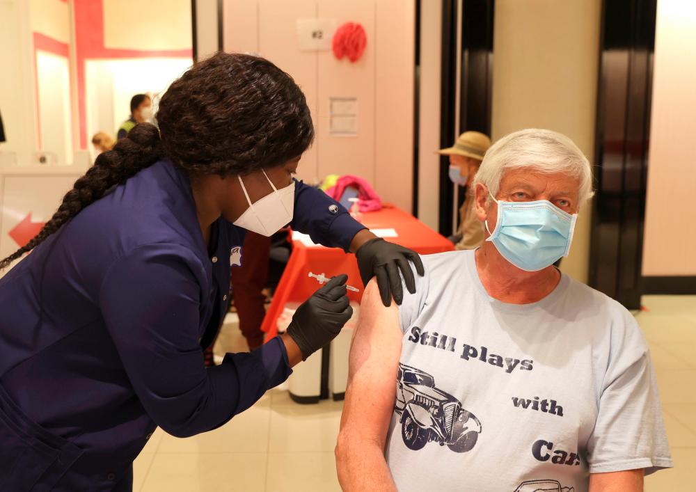 Registered nurse Barbara Dorsima (L) administers a Covid-19 booster vaccination to Mike Bagley (L) at a Covid-19 vaccination clinic on April 06, 2022 in San Rafael, California. - AFPPIX
