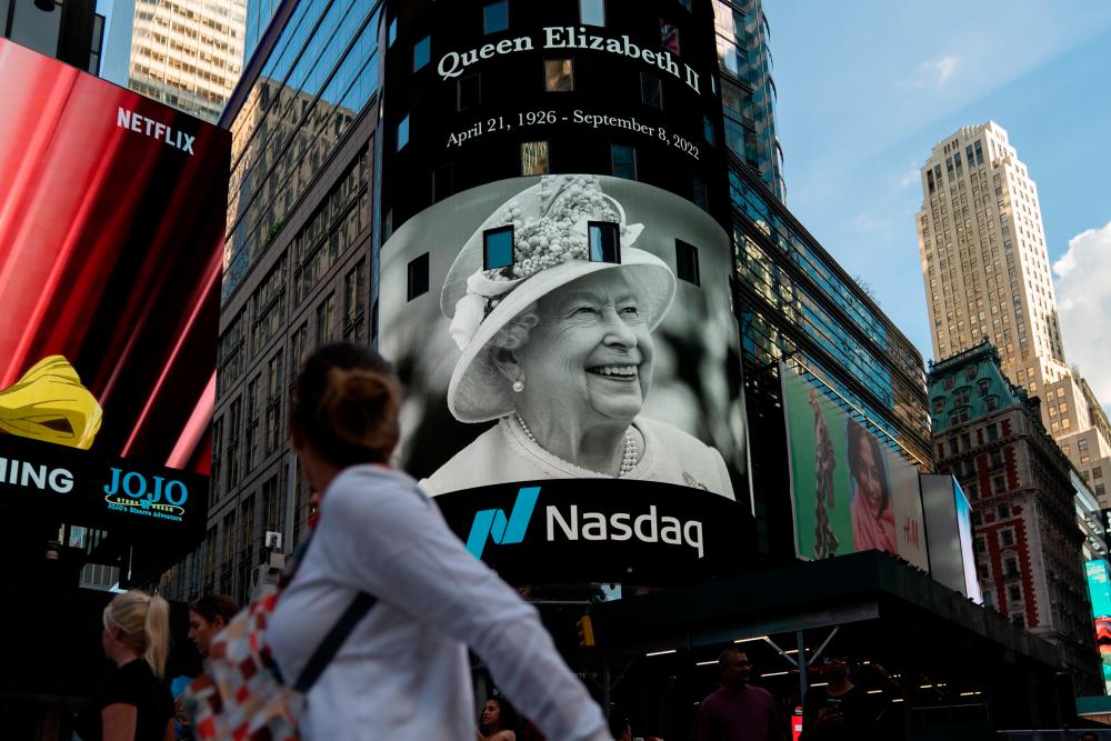 A person walks by an image of Queen Elizabeth II displayed on Times Square digital billboard on September 08, 2022 in New York City/AFPPix