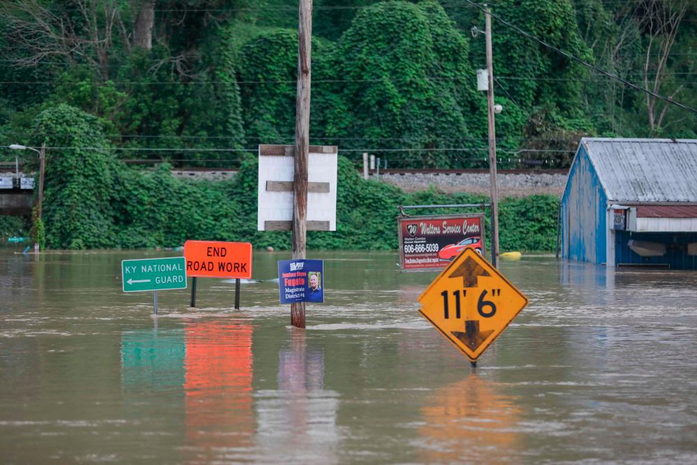 Road signs are barely visible on a road covered by floodwaters from the North Fork of the Kentucky River in Jackson, Kentucky on July 28, 2022. AFPPIX