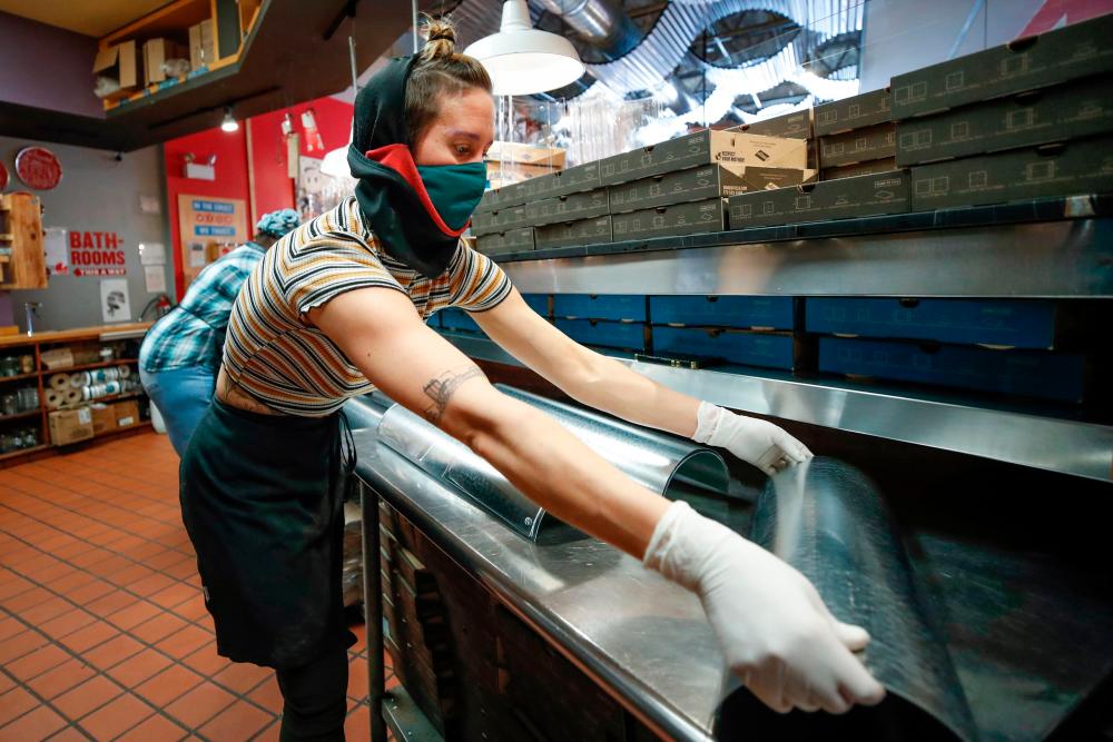 Tara Kline makes acrylic face shields for front line responders at Dimo's Pizza in Chicago, Illinois. New jobless claim filings in the United States fell to 837,000 last week, the Labor Department said.– AFPPIX