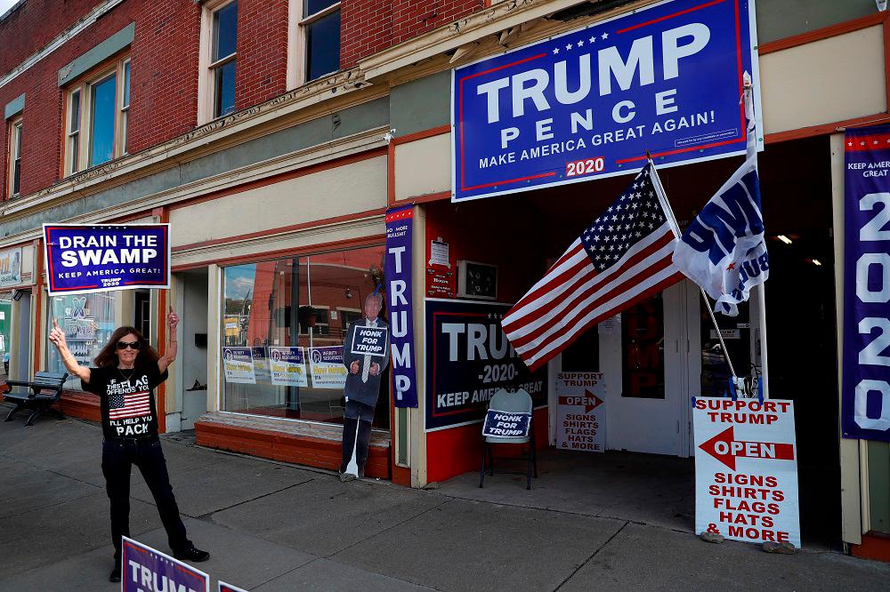 A supporter of U.S. President Donald Trump holds a campaign sign outside the Republican headquarters in Union City, Pennsylvania, U.S., October 23, 2020. -Reuters