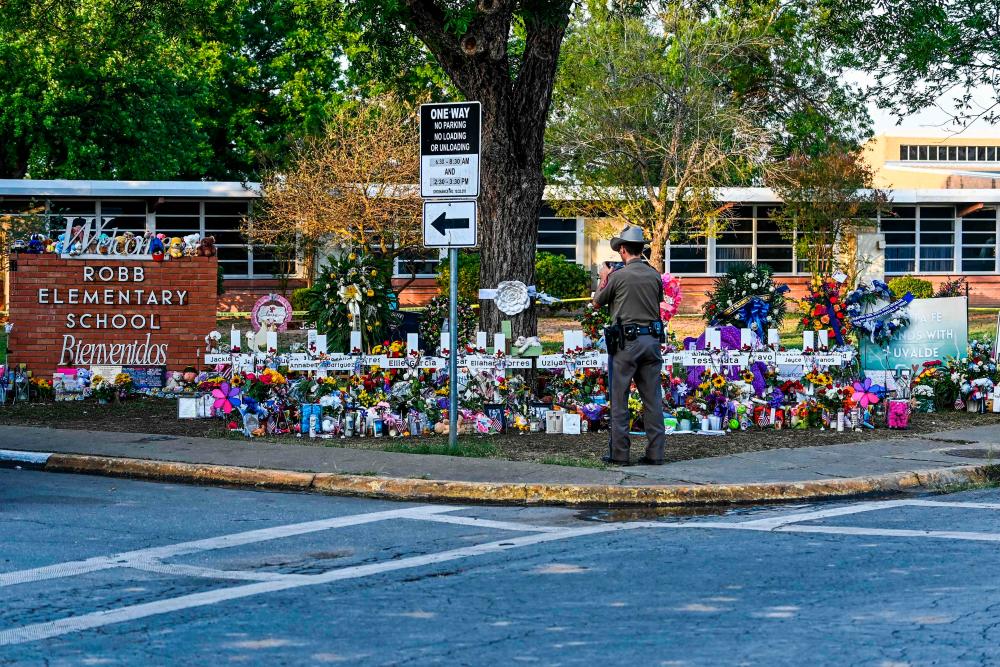 A police officer stands near the makeshift memorial for the shooting victims outside Robb Elementary School in Uvalde, Texas, on May 28, 2022. AFPpix