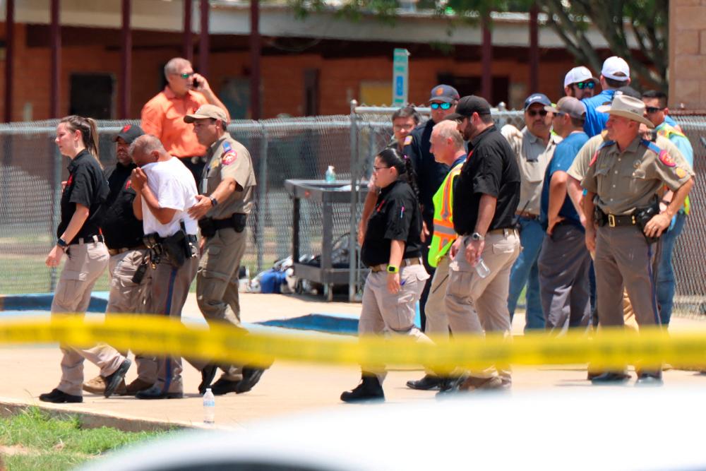 A law enforcement officer is led from the scene while a mass shooting was underway at Robb Elementary School where a gunman killed nineteen children and two adults in Uvalde, Texas, U.S. May 24, 2022.Pete Luna/Uvalde Leader-News/Handout via REUTERSpix