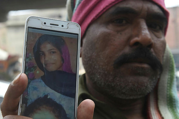 Muhammad Riaz, father of 16-year-old Uzma, a maid who was found dumped in a city canal, shows her picture on a smartphone during an interview with AFP in Lahore. — AFP