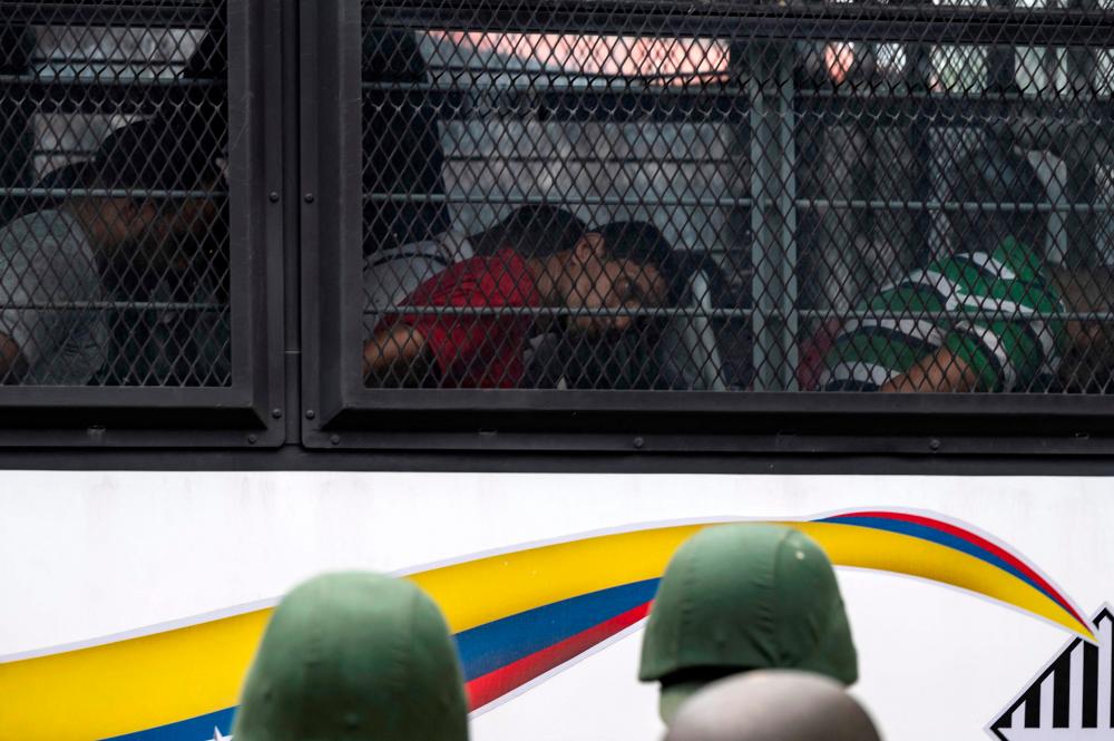 Members of the Bolivarian National Guard (GNB) stand guard as inmates aboard a bus are transferred outside the Tocoron prison in Tocoron, Aragua State, Venezuela, on September 20, 2023. AFPPIX