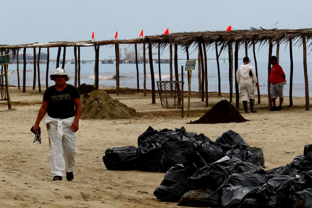 Volunteers and workers of the Venezuelan state oil company PDVSA wear protective equipment during a cleaning operation after an oil spill at the El Palito refinery in Puerto Cabello, Carabobo state, Venezuela on December 27, 2023. - AFPPIX