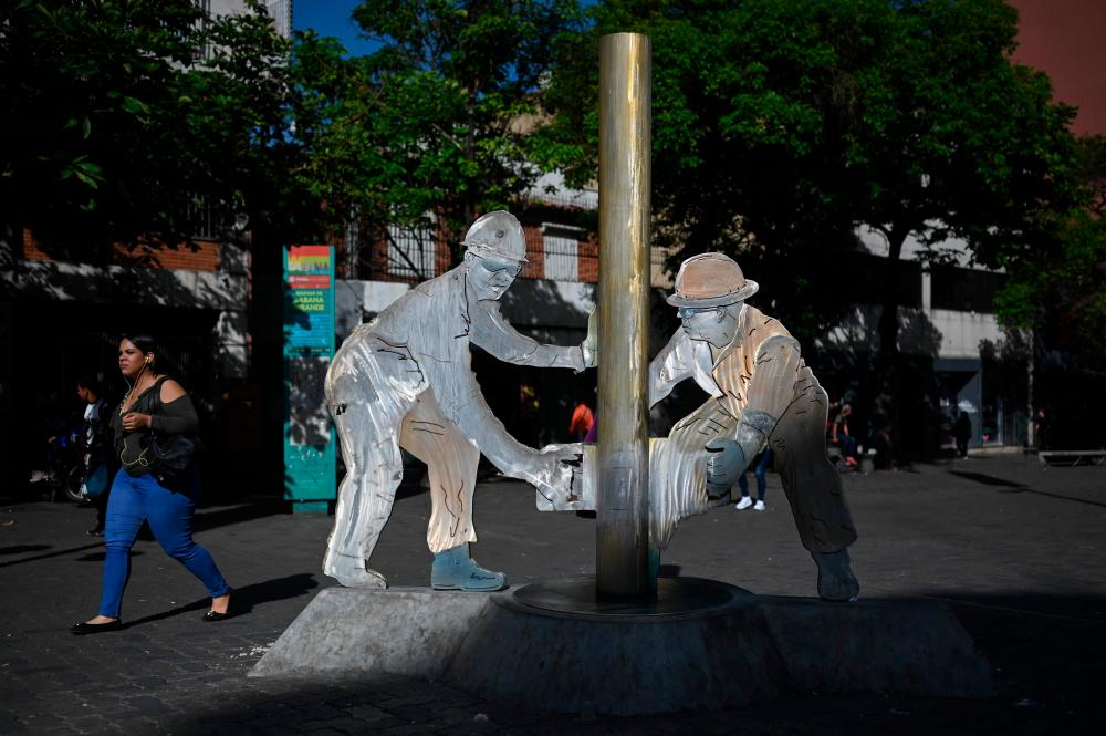 A woman walks past a sculpture depicting oil workers at Sabana Grande Boulevard in Caracas on Tuesday, June 27, 2023. – AFPpic