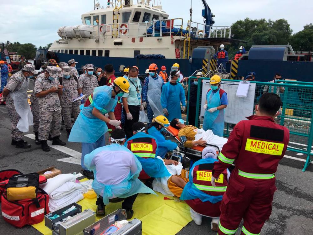 Two of the victims receiving treatment from Miri Hospital paramedics after they arrived at the Petronas Crew Change Terminal at 11.55am.-The Borneo Post