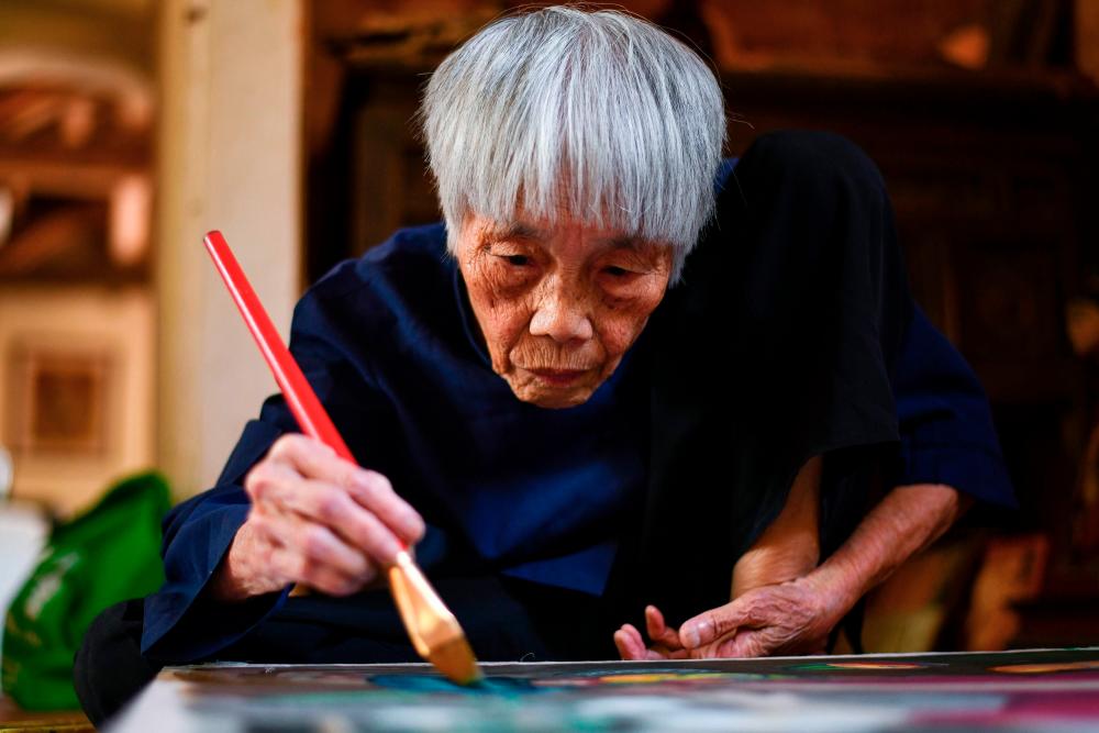 This photograph taken on October 8, 2020 shows 89-year-old Vietnamese artist Mong Bich painting at her house in Bac Ninh province, east of Hanoi. AFP / Manan VATSYAYANA