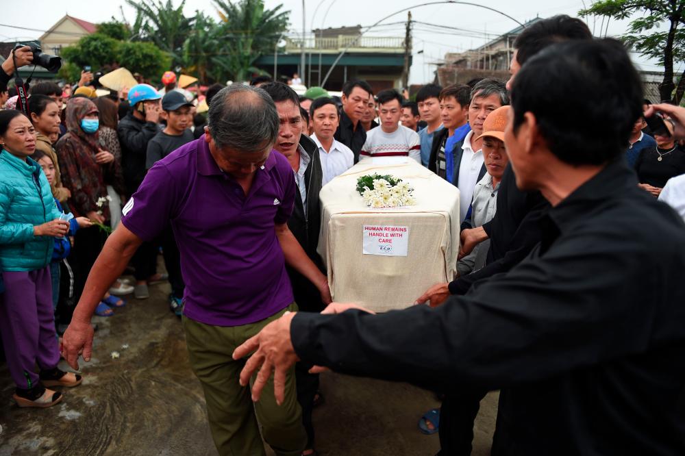 Crowds look on as relatives carry the casket bearing the body of Nguyen Van Hung arrives in Dien Chau district, Nghe An province on Nov 27, after being repatriated from Britain. — AFP