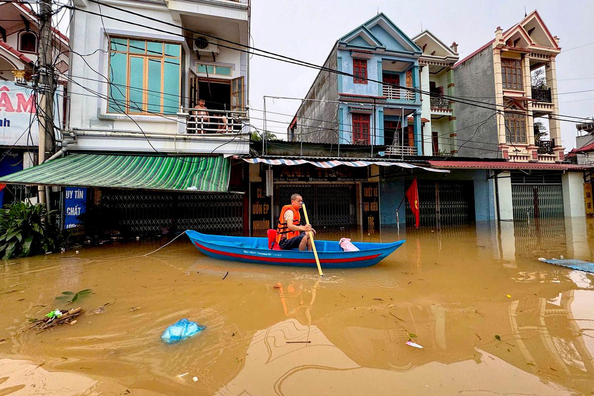 A man rows a canoe through waters past buildings in That Khe commune flooded after heavy rains caused by Typhoon Matmo in Lang Son province on October 8, 2025. (Photo by Anh TUC / AFP)
