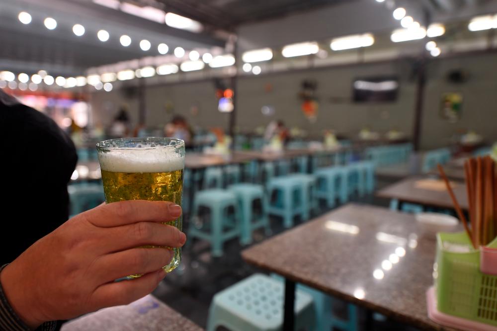 A diner holds a glass of beer at a bar in Hanoi on Jan 22. — AFP