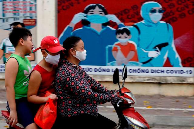 A woman wears a protective mask as she drives past a banner promoting prevention against the coronavirus disease (Covid-19) in Hanoi, Vietnam July 31, 2020. — Reuters