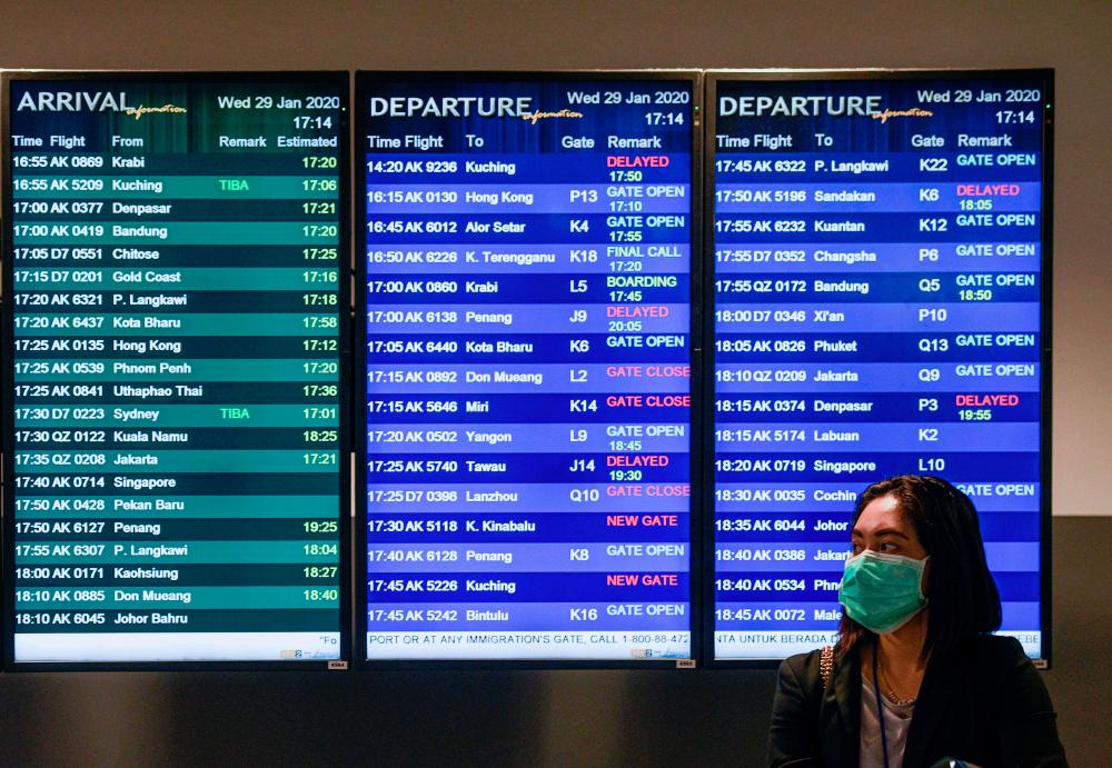 A woman wearing a face mask stands in front of the flight information screen at klia2. Tourism-related businesses, including travel and transport, are expected to be hard hit by the coronavirus outbreak, says an economist. – AFPPIX