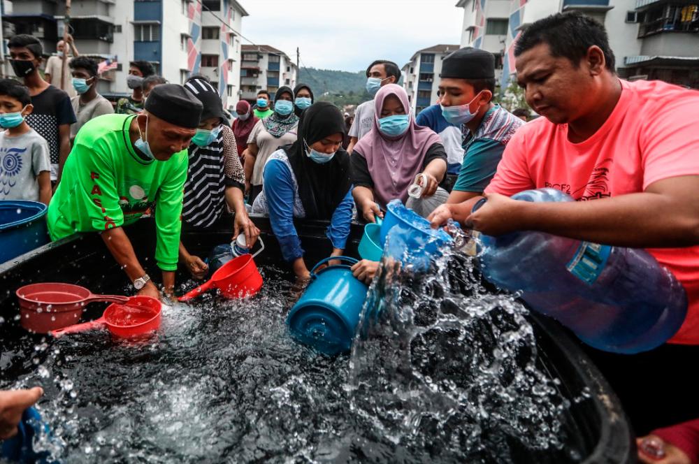 Relief rush... Residents scooping water from an open tub delivered to their flats in Batu Caves, Selangor, yesterday. The area was among several in the state that were affected by supply disruption caused by the closure of treatment plants due to river contamination.-ASHRAF SHAMSUL/theSUN