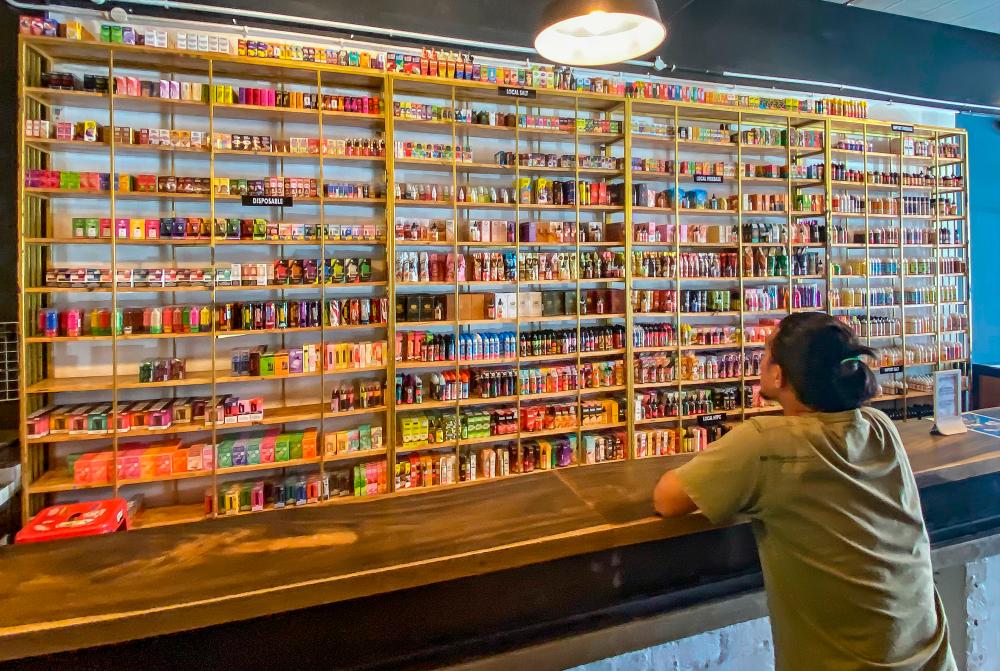 A customer looking at a wide selection of vape products, with colours, designs and flavours that are said to be appealing to children. – AMIRUL SYAFIQ/THESUN