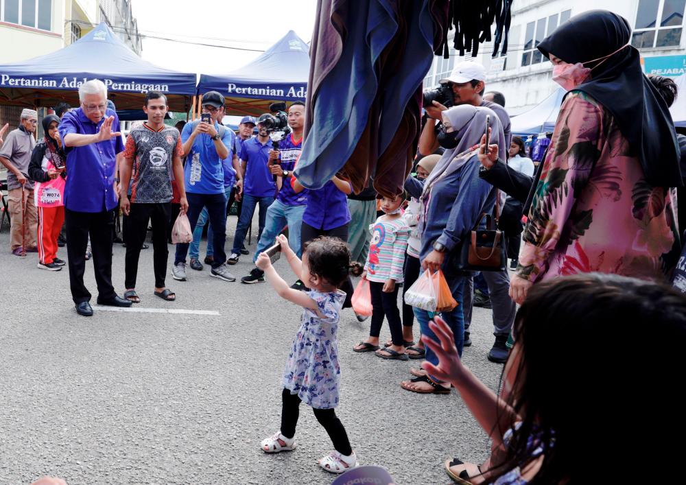 A child taking a picture of Ismail Sabri during his visit to the Kerayong Market in Bera. – BERNAMAPIC
