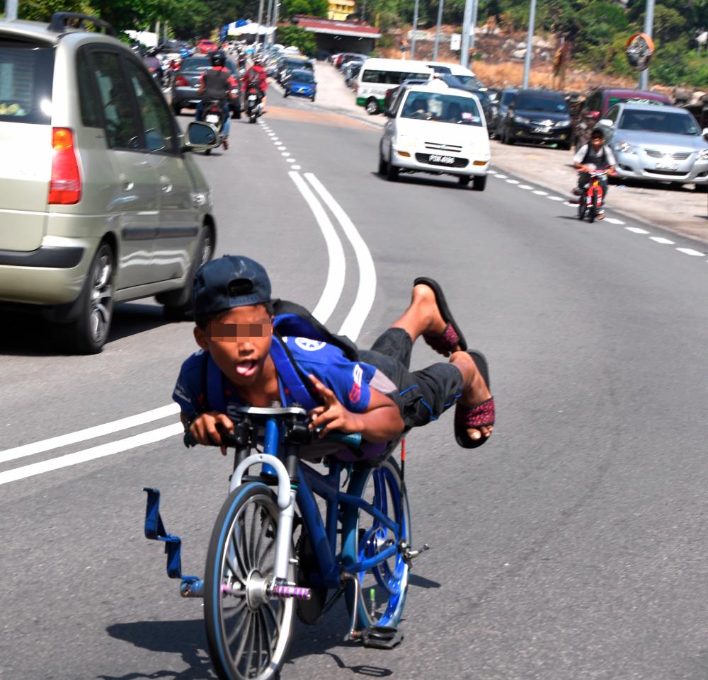 A teen on a ‘basikal lajak’, oblivious to the danger he poses to himself and motorists. – FILE PIC, March 2018