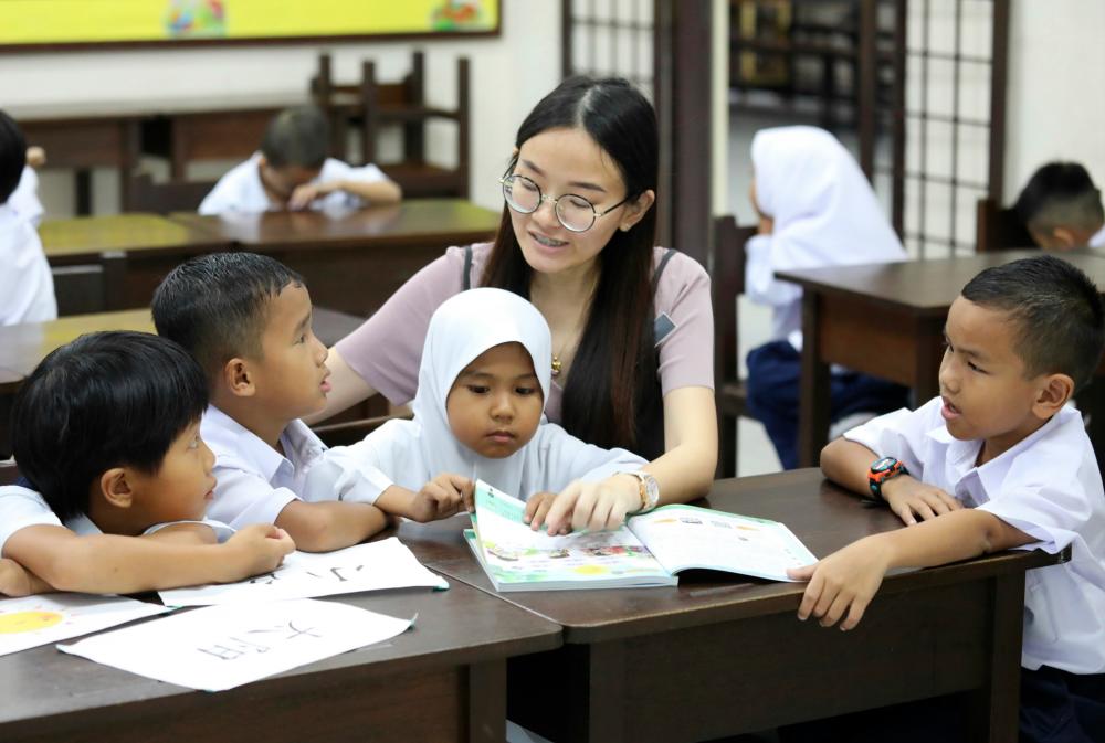 Teacher Ho Lee Lin paying special attention to three non-Chinese pupils - (second from left, Muhammad Danial Hairulhazizal, Dhiieya Qistieyna Haizat and Iman Hadeef Haniz - during a Mandarin class at SJKC Aik Keow in Penang. – Masry Che Ani/theSun