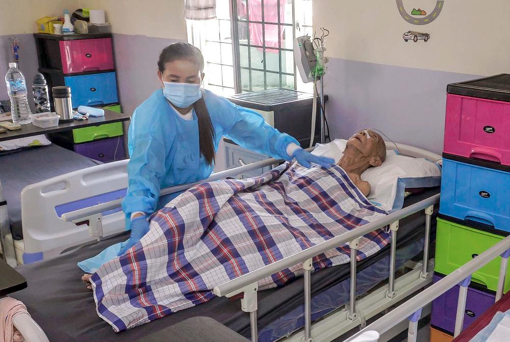 A caregiver at Fupin ensuring a resident is comfortable. – ADIB RAWI YAHYA/THESUN