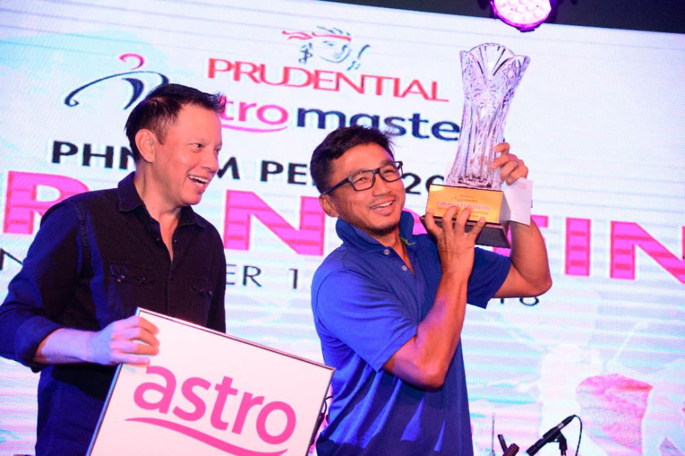 The joy of victory ... Mohd Hezri Md. Hassan lifts the gross champion’s trophy as Datuk David Yap of Astro looks on.