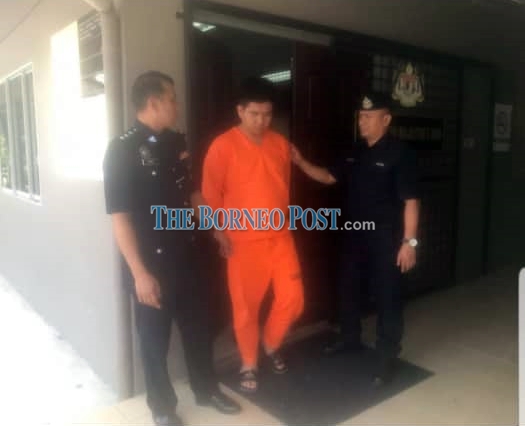 Chong is escorted by the police at the Bau magistrate’s court this morning. — Borneo Post photo