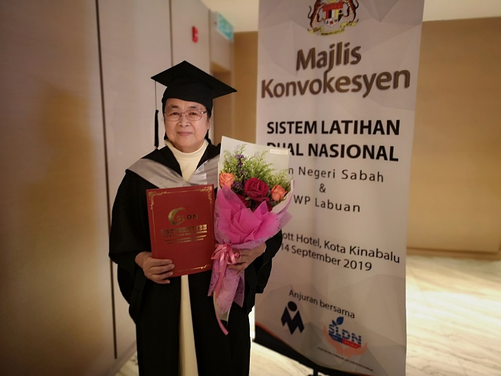Sister Rufina with her certificate and a bouquet during the Sabah and Labuan FT National Dual Training System convocation yesterday. — Borneo Post