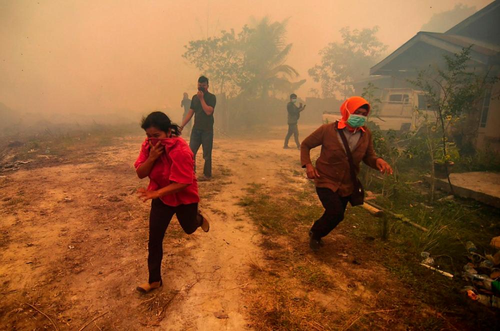 Villagers flee as a forest fire rages near their village in Kampar, Riau on Sept 22, 2019. — AFP