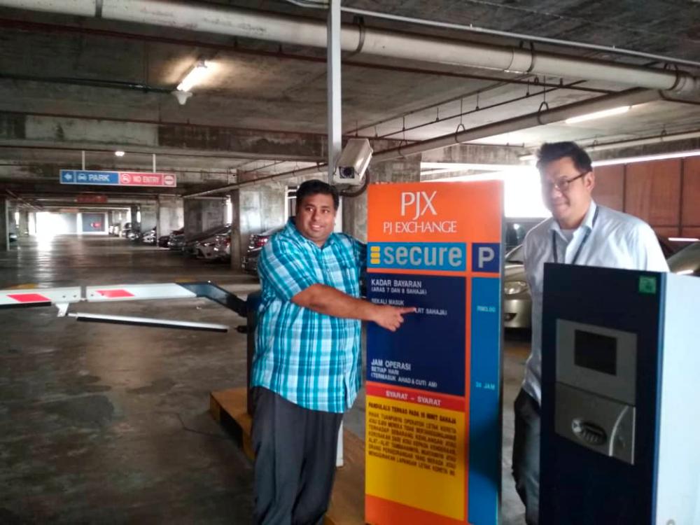 Bukit Gasing assemblyman Rajiv Rishyakawan pointing towards the parking rates notice in a car park at PJX HM Shah Alam in Petaling Jaya, today