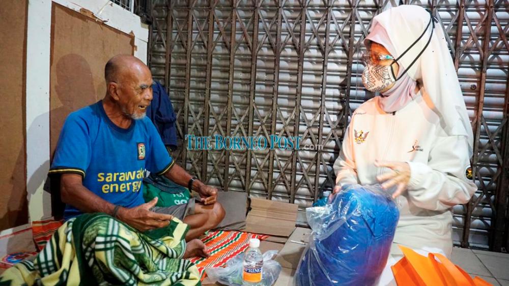Fatimah (right) speaking to a senior citizen found living on the streets during the operation last night.- Borneo Post