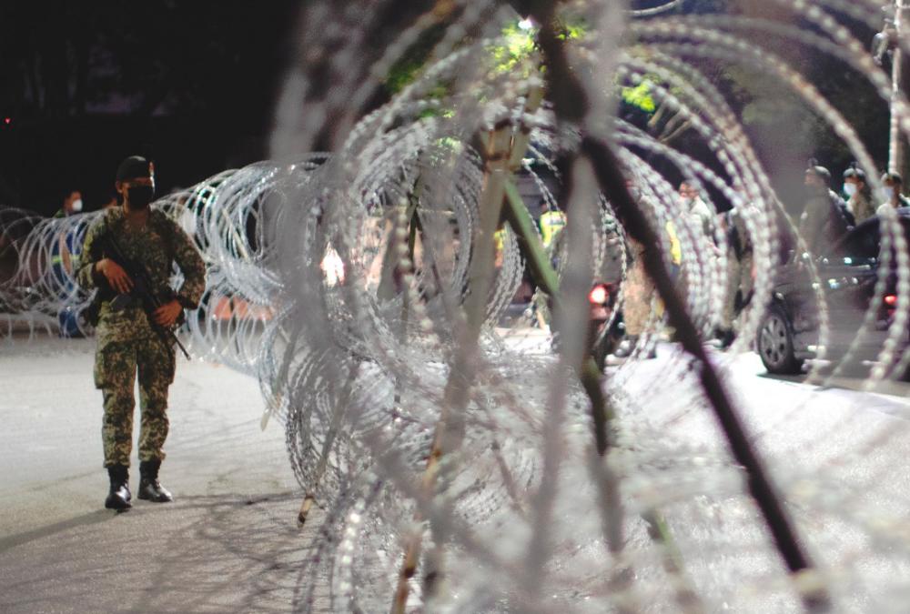 $!TIGHT SECURITY... A soldier standing guard alongside barbed wires at Kampung Sungai Penchala in Kuala Lumpur, which was placed under enhanced movement control. - NORMAN HUI/THESUN