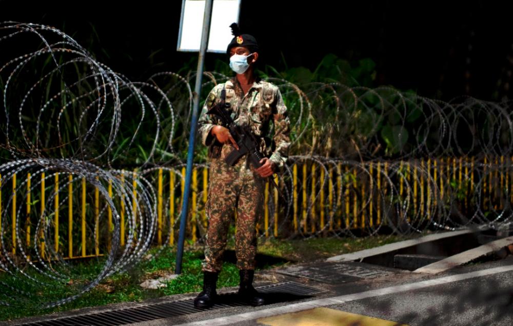 $!TIGHT SECURITY... A soldier standing guard alongside barbed wires at Kampung Sungai Penchala in Kuala Lumpur, which was placed under enhanced movement control. - NORMAN HUI/THESUN