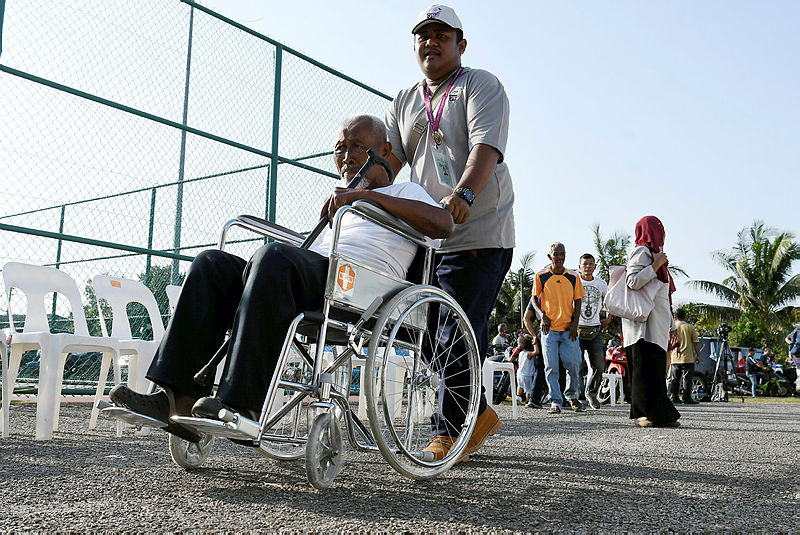 A wheelchair-bound voter is being assisted to the polling station, on March 2, 2019. — Bernama