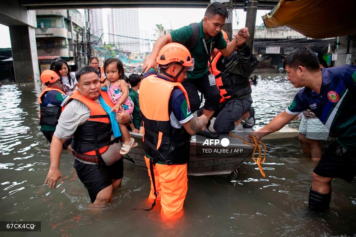 Rescuers use a boat to evacuate stranded people through a flooded street in Manila on July 21, 2025, after Typhoon Wipha brought heavy rains and flooding to the Philippines, where two people have been reported missing, according to the country's National Disaster Risk Reduction and Management Council. - Ted ALJIBE / AFP