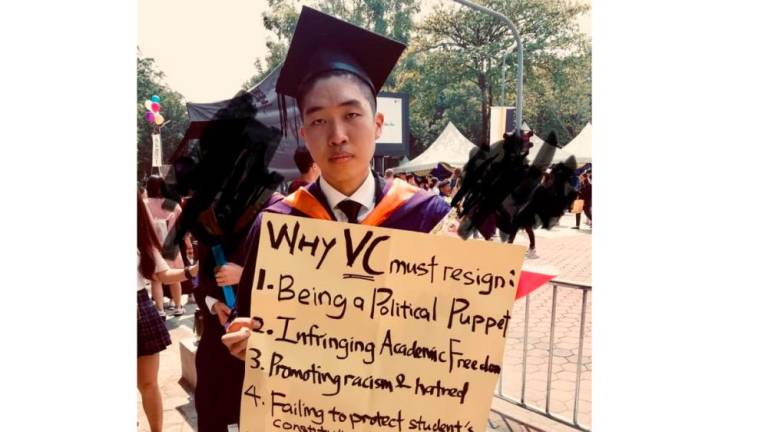 Wong Yan Ke with the protest placard that he carried on stage when receiving his scroll.