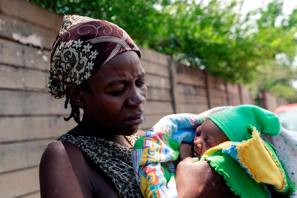 Winnie Denhere cradling her two-day-old baby boy delivered by Esther Gwena outside Edith Opperman clinic where the baby is to receive a BCG vaccine injection in Mbare high-density suburb in Harare, on Nov 21, 2019. — AFP