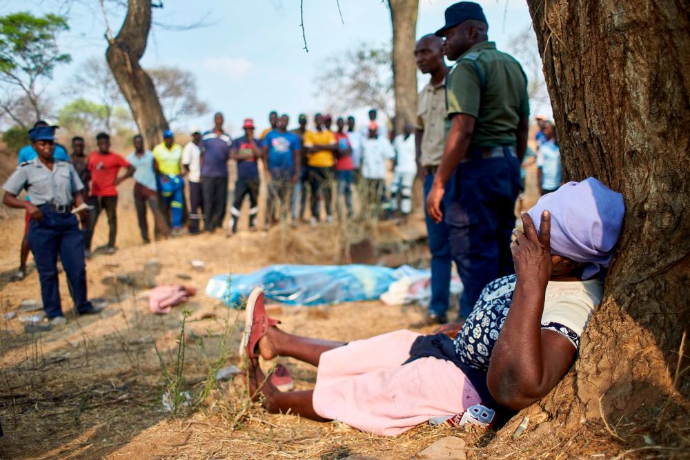 A distraught woman collapses after identifying the body of a miner strapped on a stretcher after a gold mine shaft collapsed at the Bay Horse mine in Chegutu, Zimbabwe on September 30, 2023. - AFPPIX