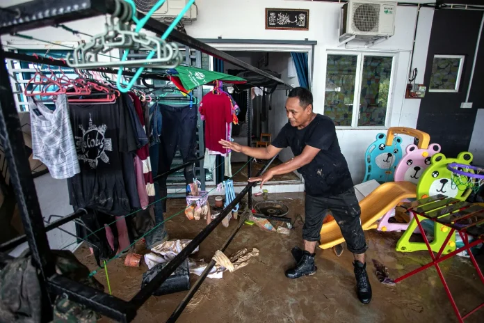 Flood victim Suhaziman Mohd Suhaimi, 35, cleaning his house affected by floods at Taman Larah Damai on October 24 - BERNAMAPIX