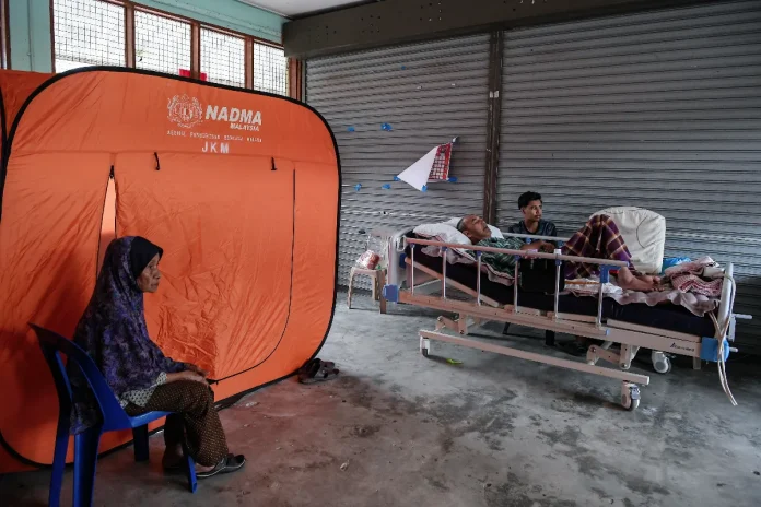 Muhammad Haris Azmi, 17 with his father, Azmi Hashim, 57, who is bedridden due to a stroke - BERNAMAPIX