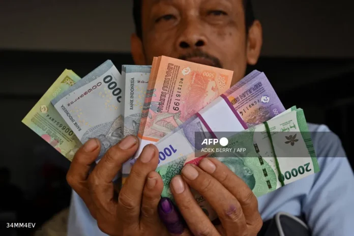 A man shows his new Rupiah bank notes, to be given to family members during the Eid festival which marks the end of the holy month of Ramadan, in Jakarta on March 28, 2024. - AFP file pic