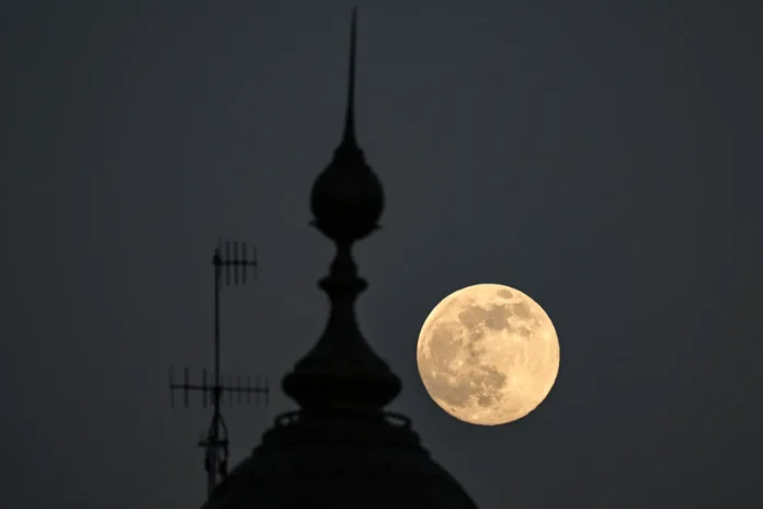 The supermoon known as the Beaver Moon is seen next to the dome of a historic building in Mexico City on November 4, 2025. - AFP