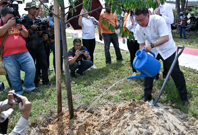 Minister of Housing and Local Government Nga Kor Ming (right) watering the symbolic tekoma tree to open the MADANI Boon Bak Recreation Park today.